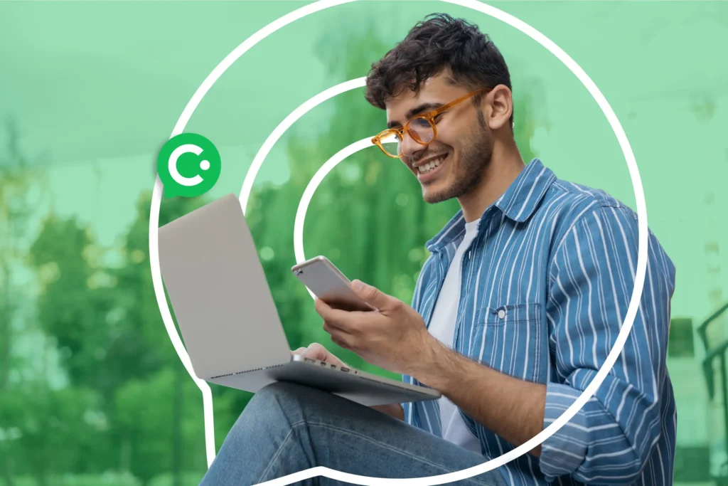 Smiling man looking at his phone while using on his laptop